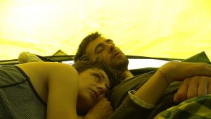 Frau und Mann liegen zusammen in einem grünem Zelt.