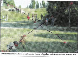 Eine pixelige Postkarte zeigt Menschen in einem Park. Über das Bild ist ein Kreuz gemalt.