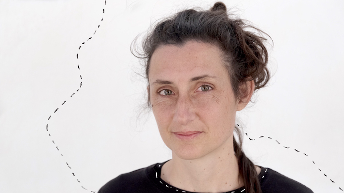 Angelika Herta Portrait Lächelnde Frau um die 40 mit dunkelbraunen Haaren in einem lockeren Haarknoten.