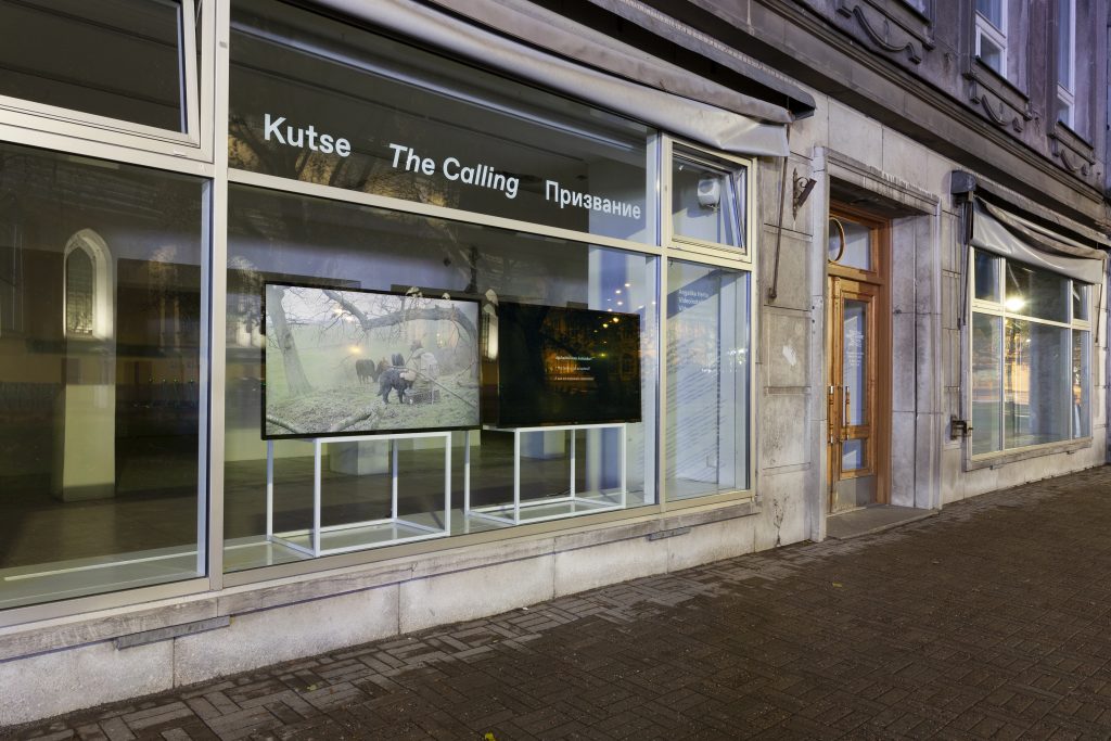 Installationsansicht von “The Calling” mit zwei Bildschirmen im Schaufenster einer Galerie.